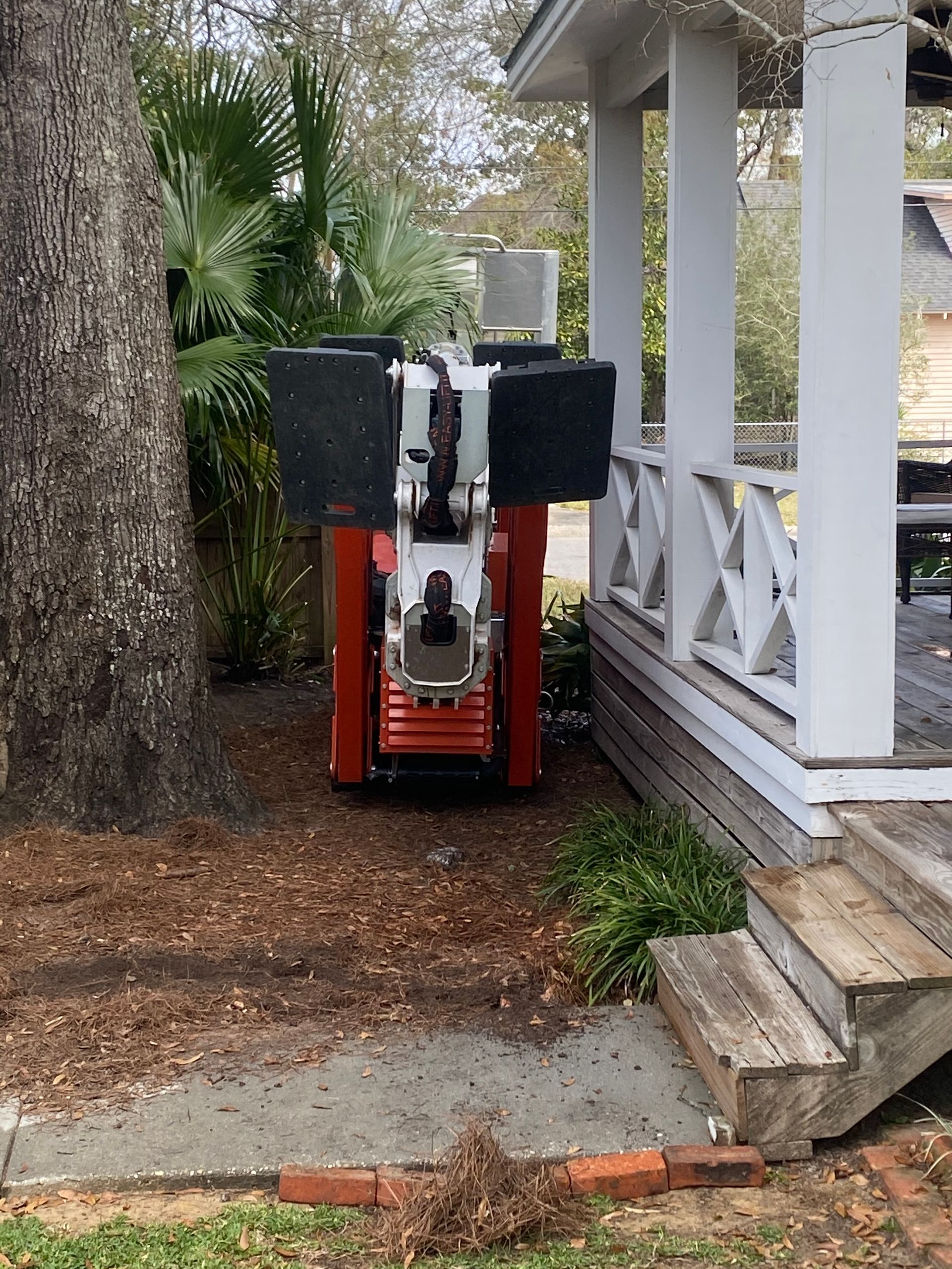 A red and white machine is parked in front of a porch.