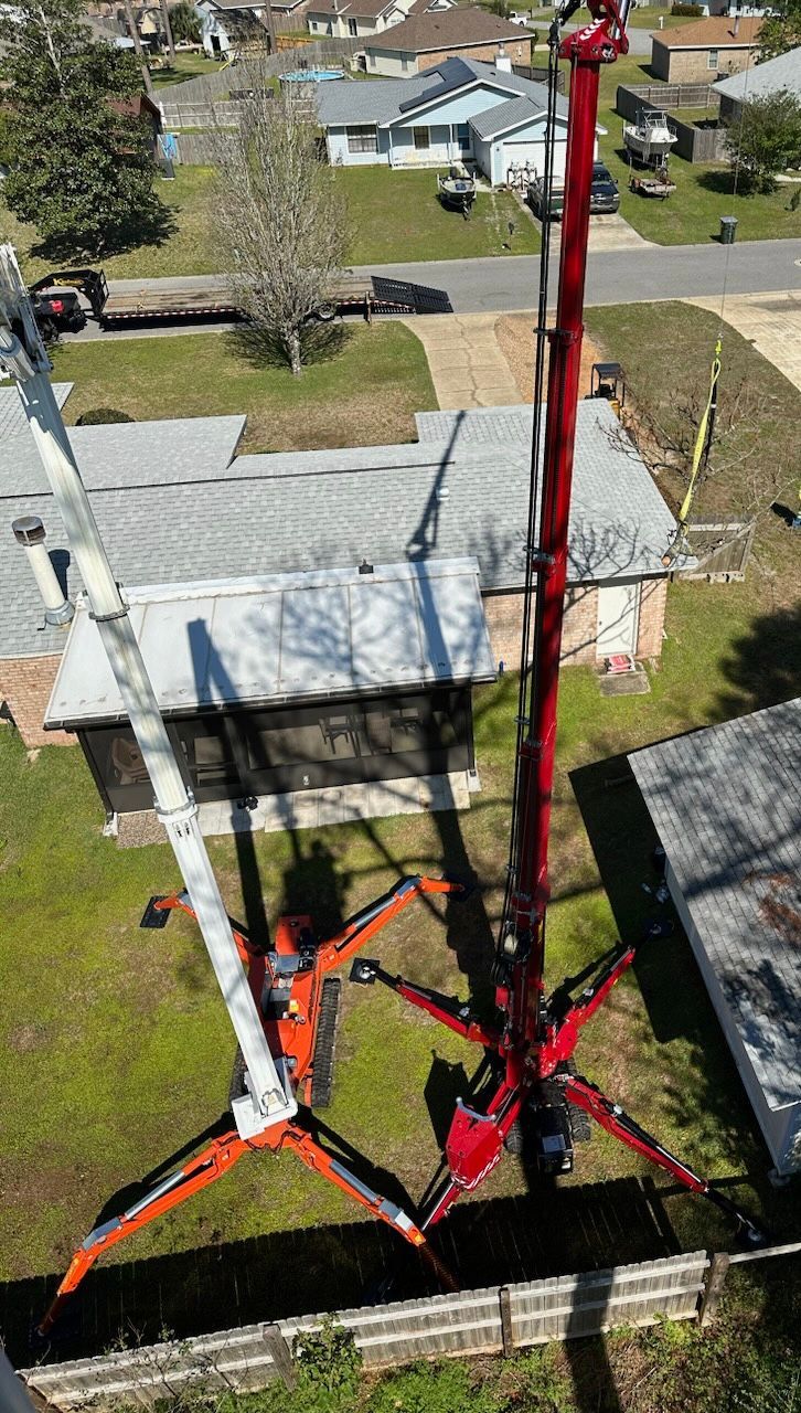 An aerial view of a crane working on the roof of a house.
