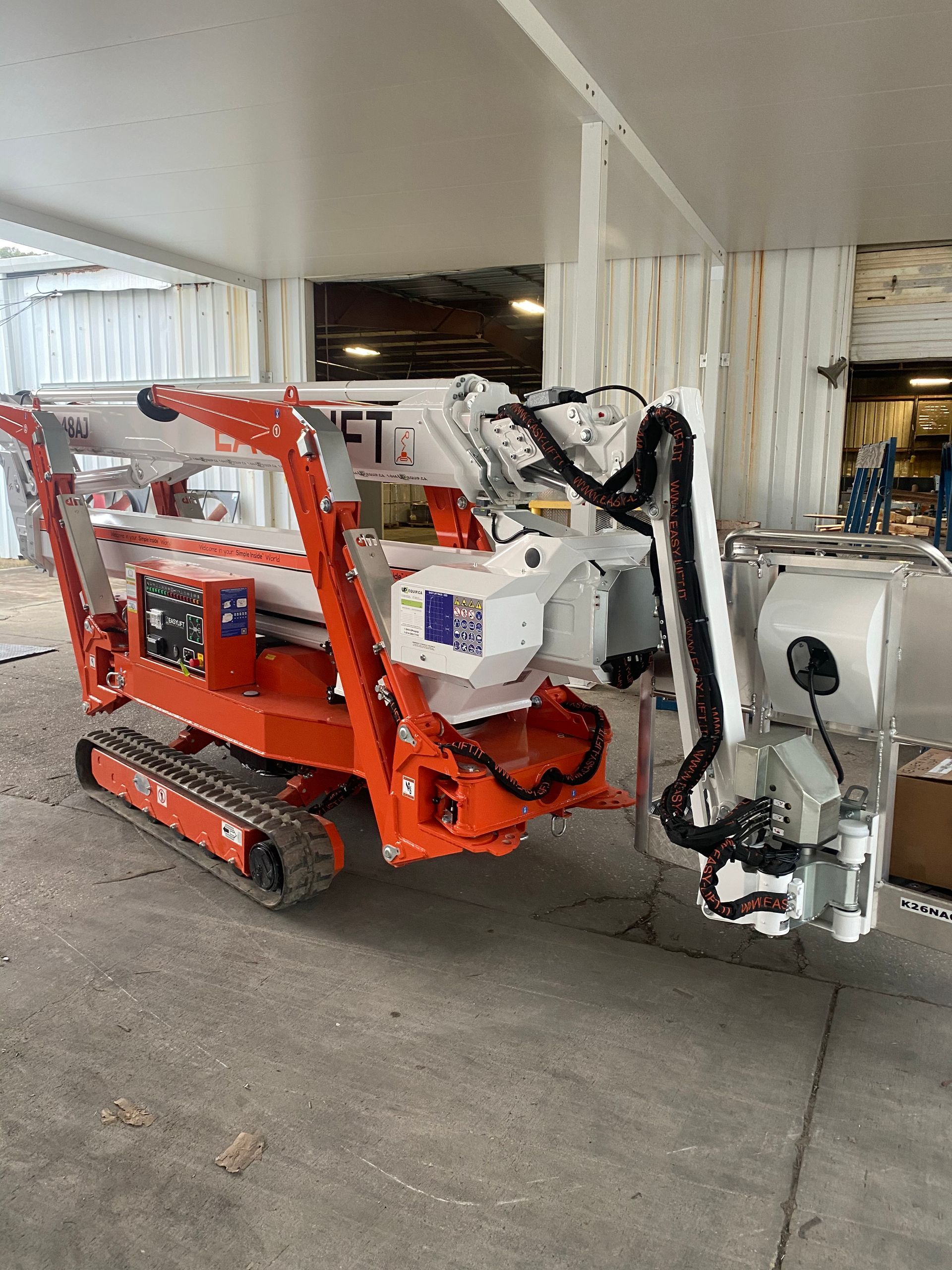A small orange and white crane is parked in front of a building.