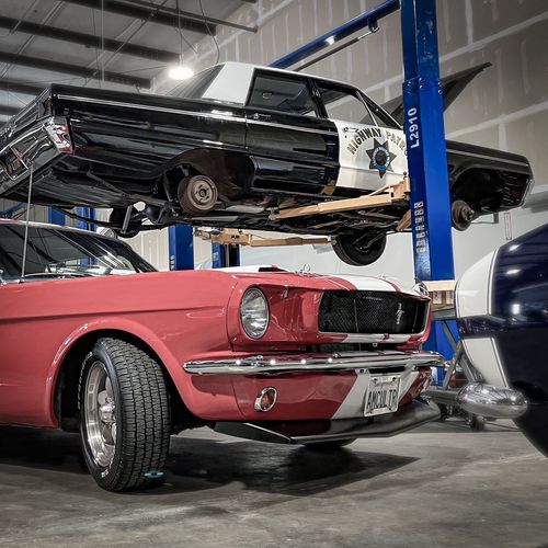 Dark gray race-modified Cadillac CTS sedan with racing numbers in a garage with other vehicles | Gilroy Car Care