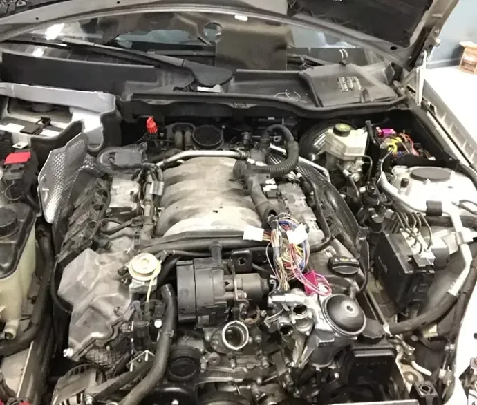 Engine bay of a car with various components visible, including wires and manifolds. Gray setting | Gilroy Car Care