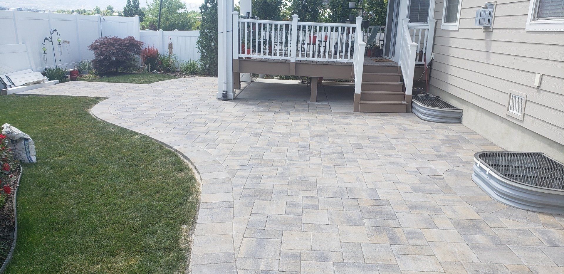 A patio with a deck and stairs in the backyard of a house.