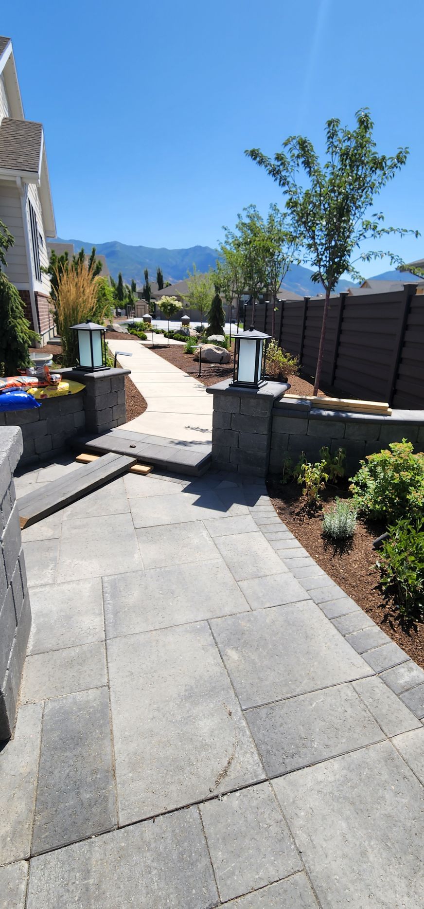 A walkway leading to a house with a fence and mountains in the background.
