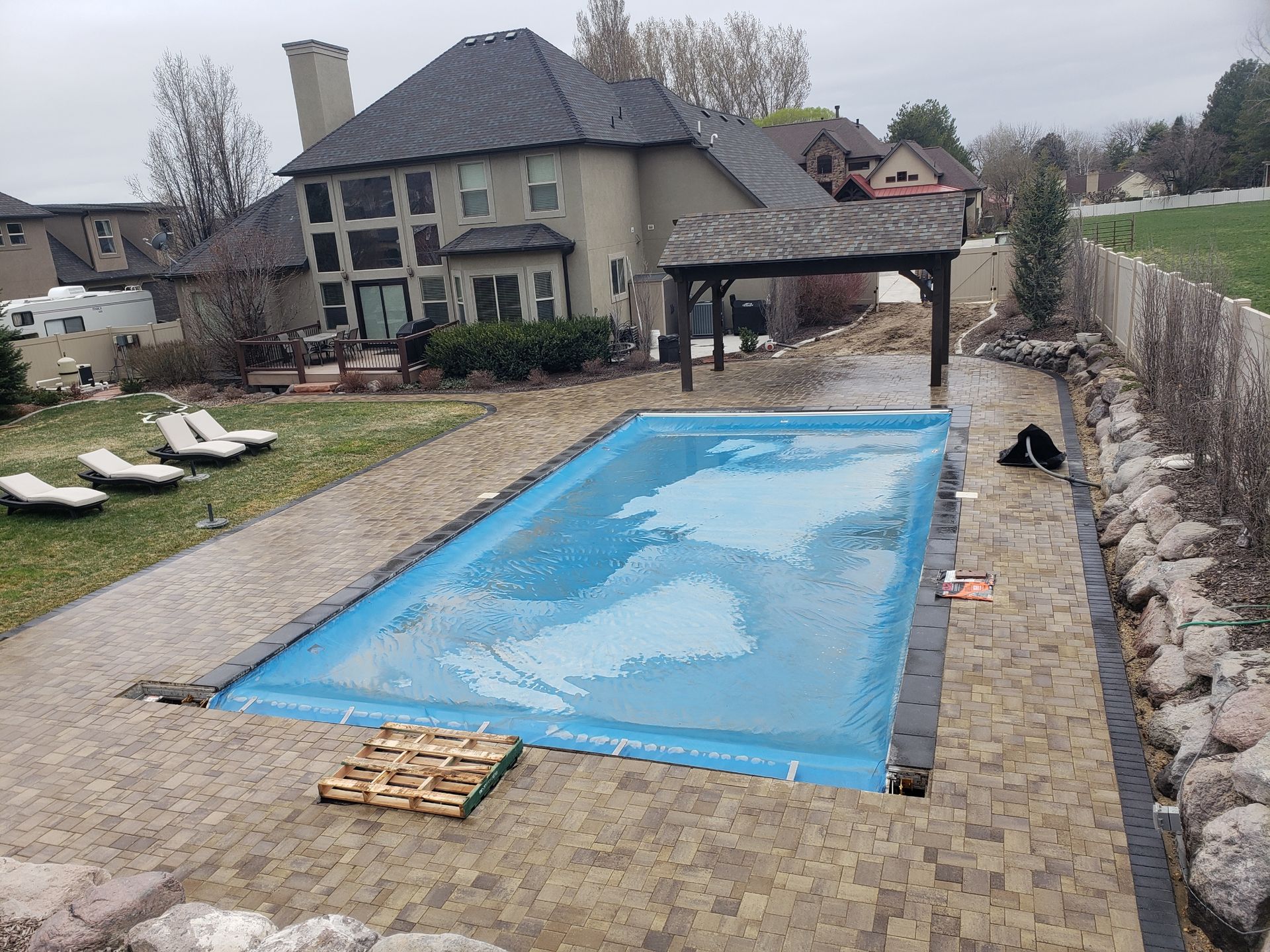 A large swimming pool is in the backyard of a house.