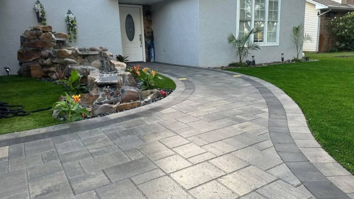 A brick driveway with a concrete driveway in the background