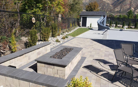 A fire pit is surrounded by a stone wall and a bench.
