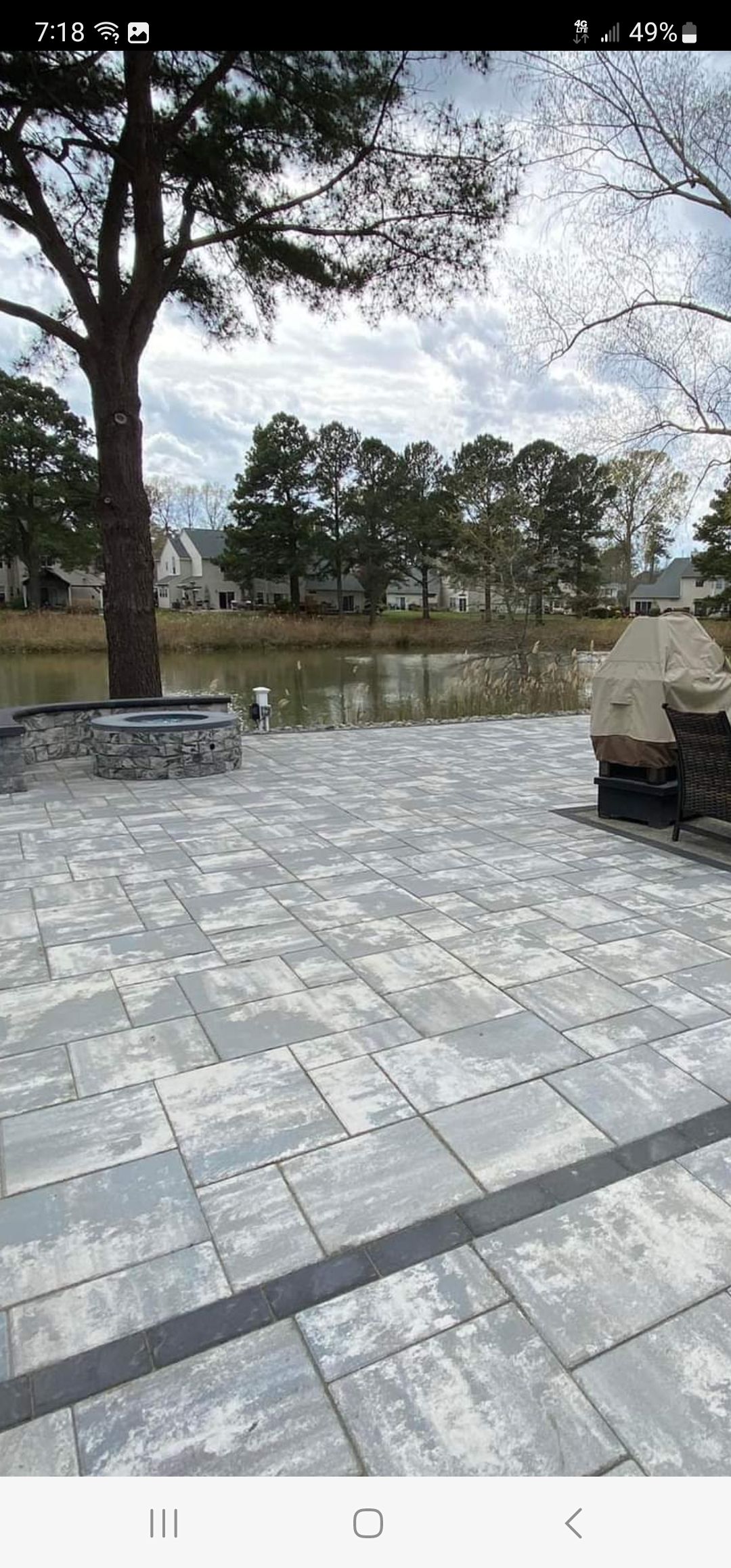 A patio with a tree and a lake in the background.