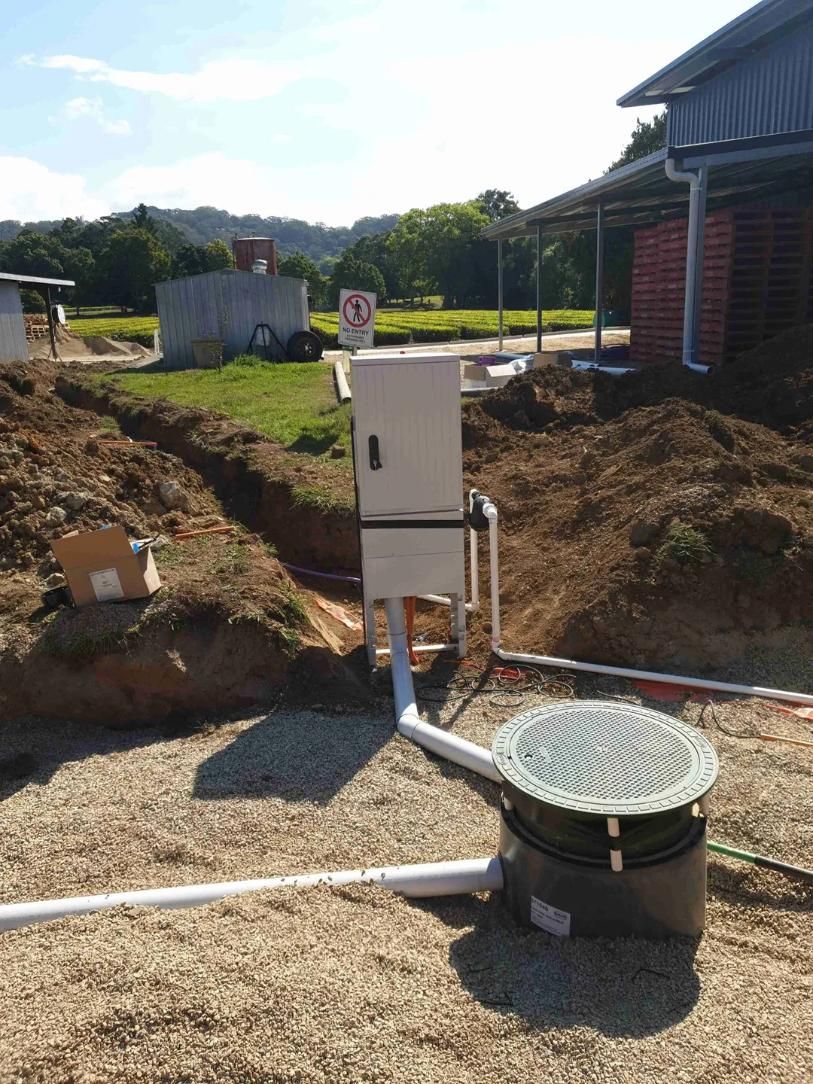 A Manhole Cover Is Sitting in The Dirt in Front of A House — Murwillumbah District Plumbing Service in Tyalgum, NSW