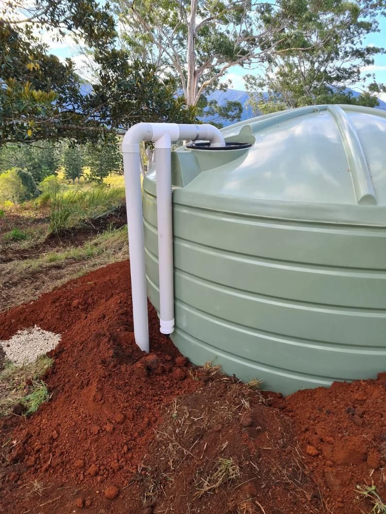 A Green Water Tank Is Sitting on Top of A Pile of Dirt — Murwillumbah District Plumbing Service in Nunderi, NSW