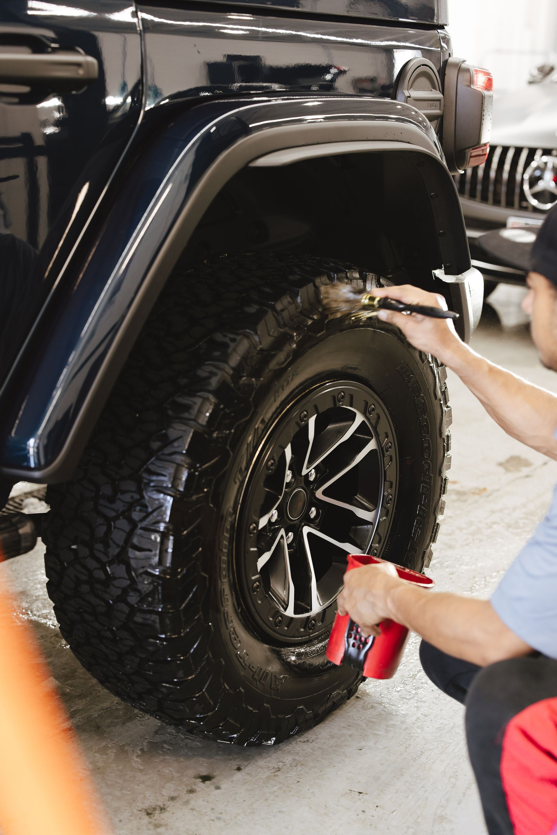 A stack of tires in a garage with cars in the background.