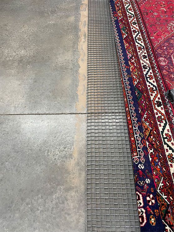 A rug is sitting on top of a concrete floor next to a rug.