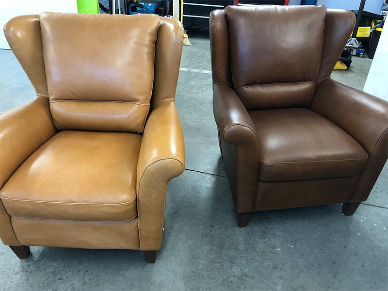 Two brown leather chairs are sitting next to each other on a concrete floor.