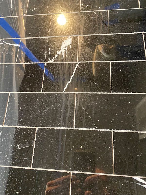 A black tile floor with a reflection of a person in it.