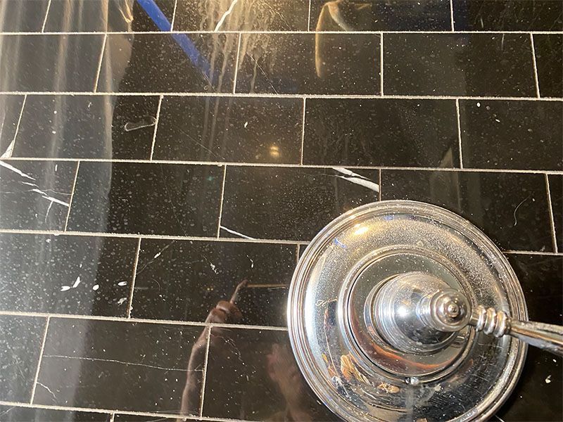 A close up of a shower head on a tiled floor