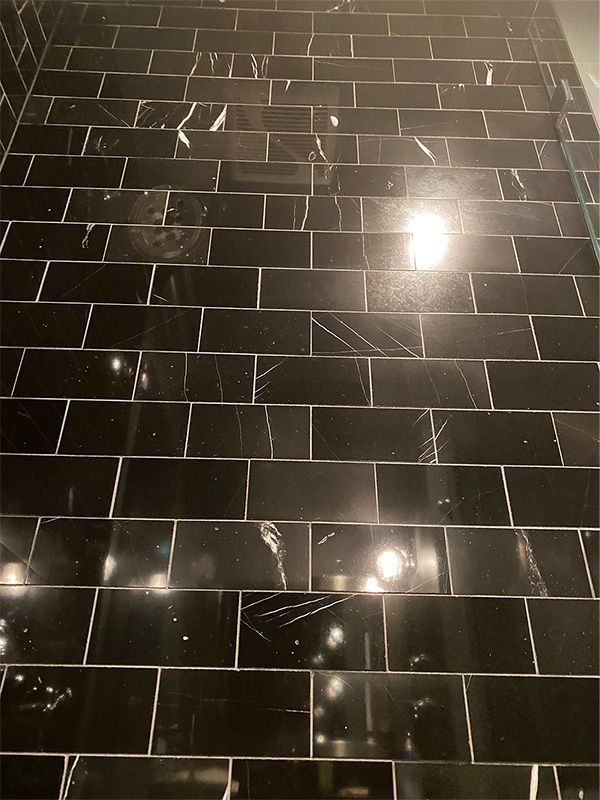 A row of black tiles on a wall with a light shining through them