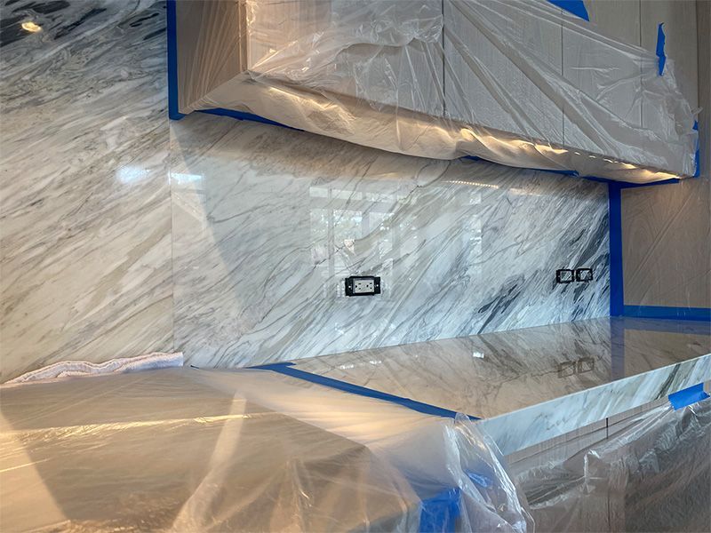 A room with a marble counter top and a wall covered in plastic.