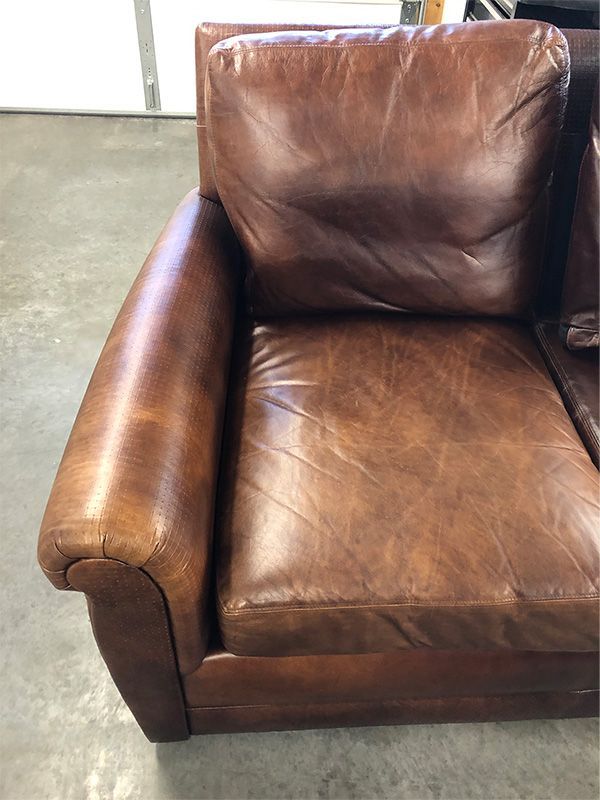 A brown leather chair is sitting on a concrete floor.