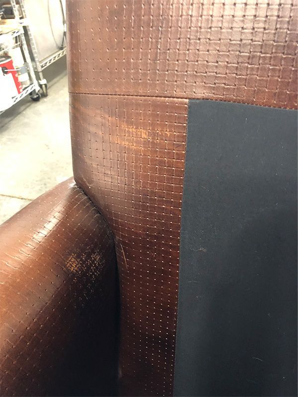A close up of a brown leather chair with a black cushion