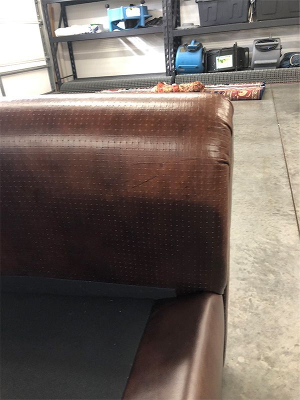 A brown leather couch is sitting in a garage.