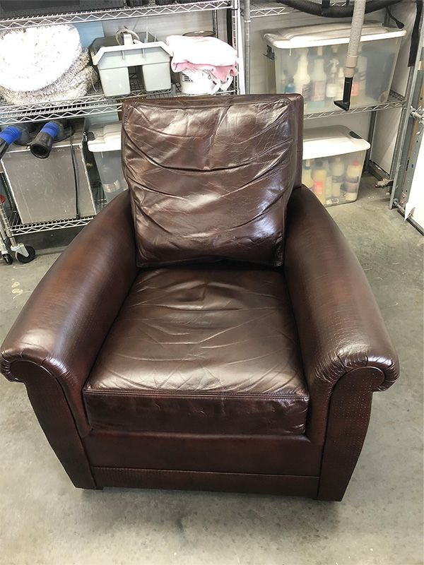 A brown leather chair is sitting in a garage.