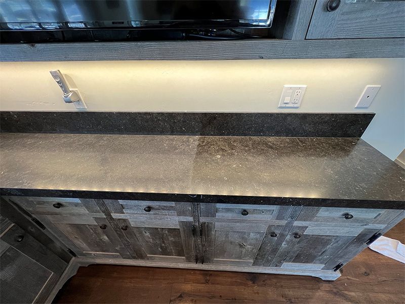 A kitchen counter with a black granite counter top and wooden cabinets.