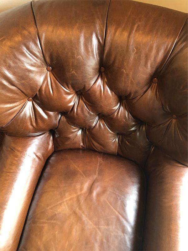 A close up of a brown leather chair with buttons on it