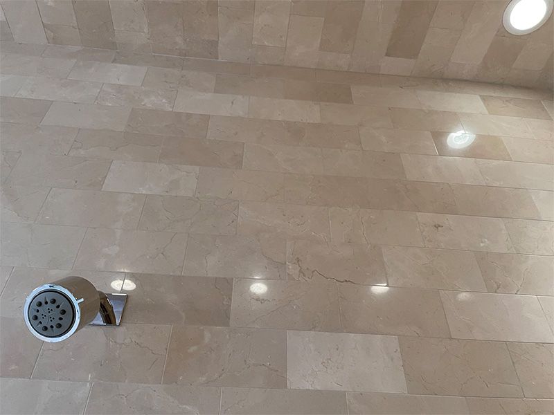 A shower head is sitting on a tiled floor in a bathroom.