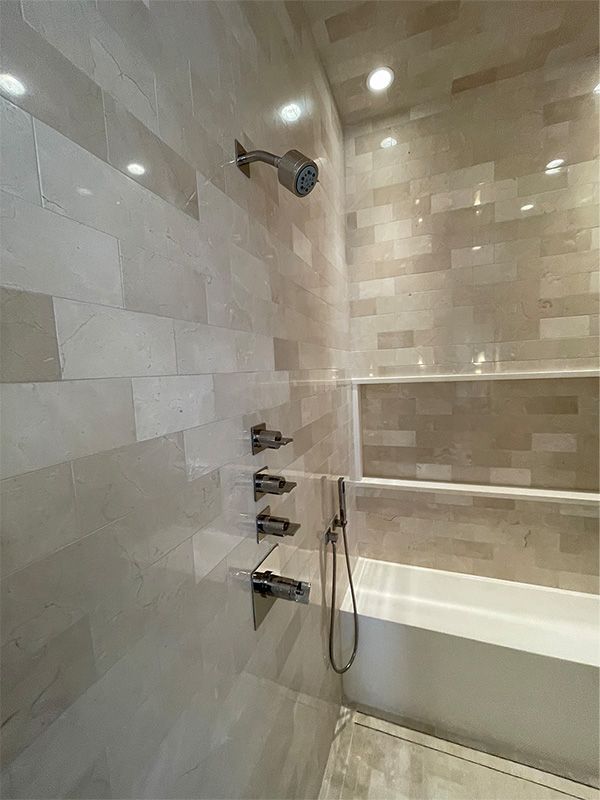 A bathroom with a tub , shower , and tiled walls.