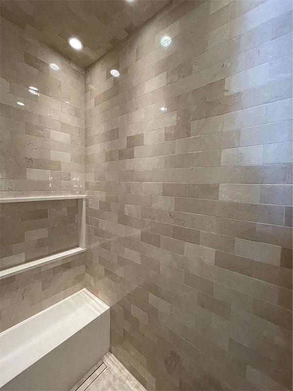 A bathroom with a tub , shower , and tiled walls.