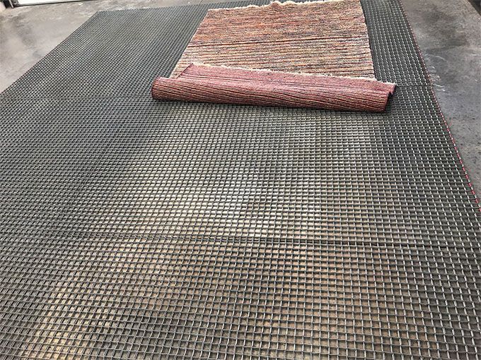 A rug is rolled up on top of a metal mat.