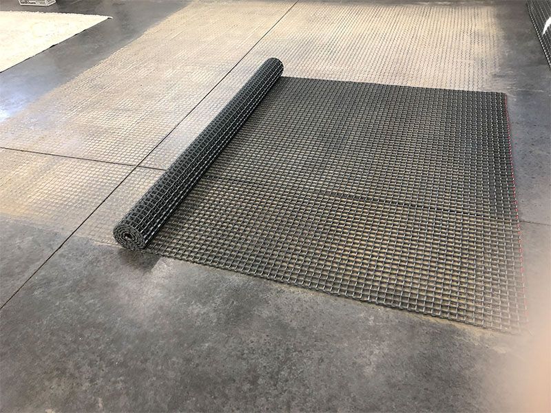 A roll of rubber mat is sitting on a concrete floor.