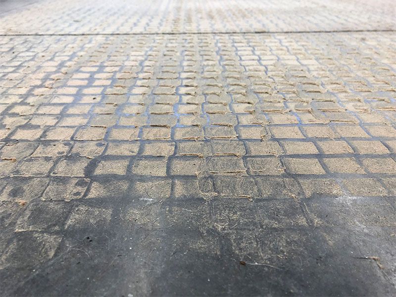 A close up of a brick pavement with a shadow on it
