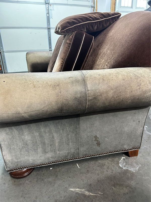 A couch is sitting on a concrete floor in front of a garage door.