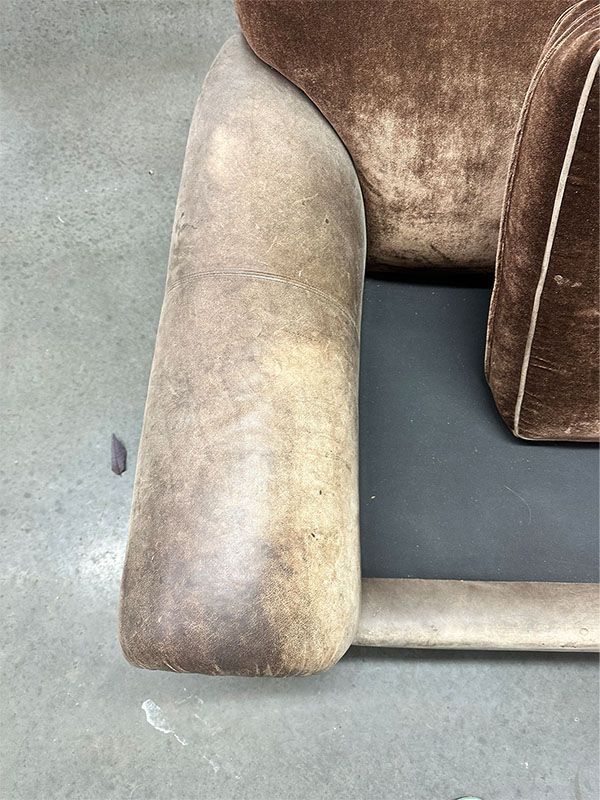 A brown leather chair is sitting on a concrete floor.