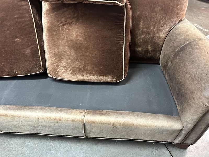 A brown couch with a black cushion on the floor