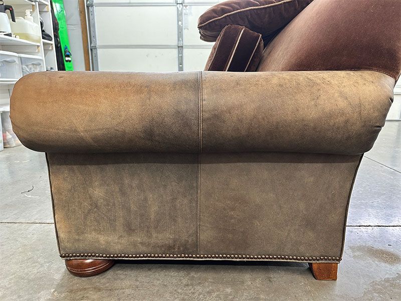 A brown leather chair is sitting on a concrete floor