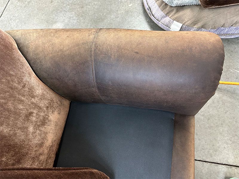 A brown leather couch is sitting on a concrete floor.