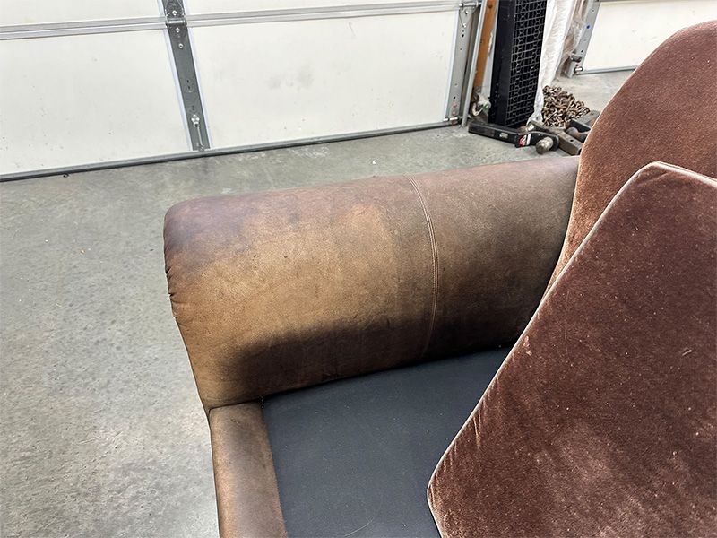 A brown leather chair is sitting in front of a garage door