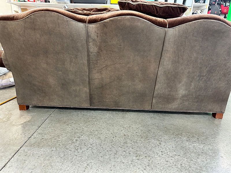 A brown couch is sitting on a concrete floor.