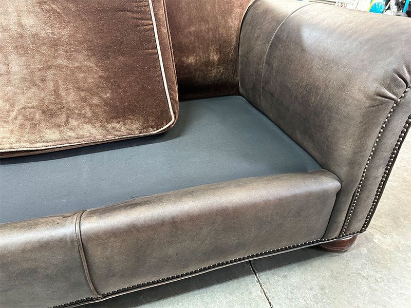 A brown leather couch with two pillows on it