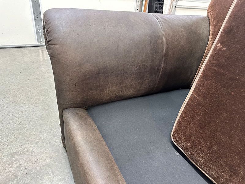 A brown leather couch with a brown pillow on it
