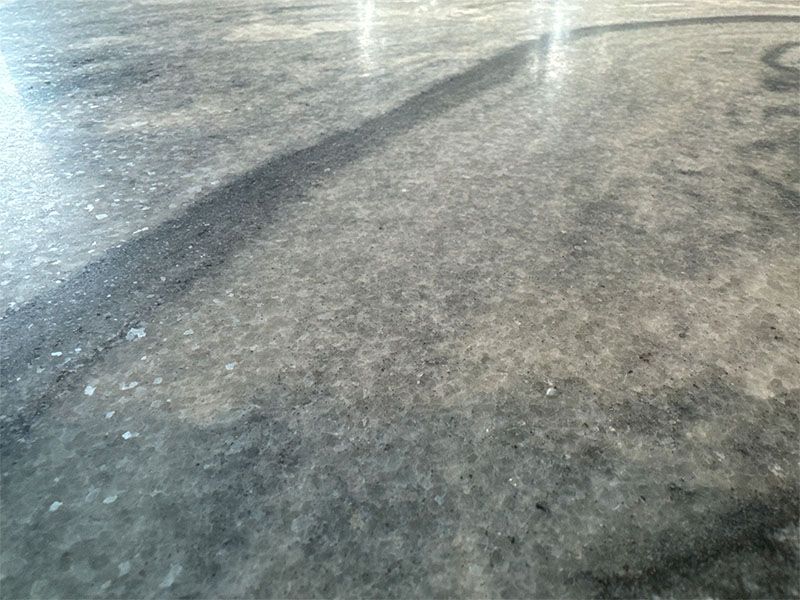 A close up of a gray concrete floor with a shadow on it.