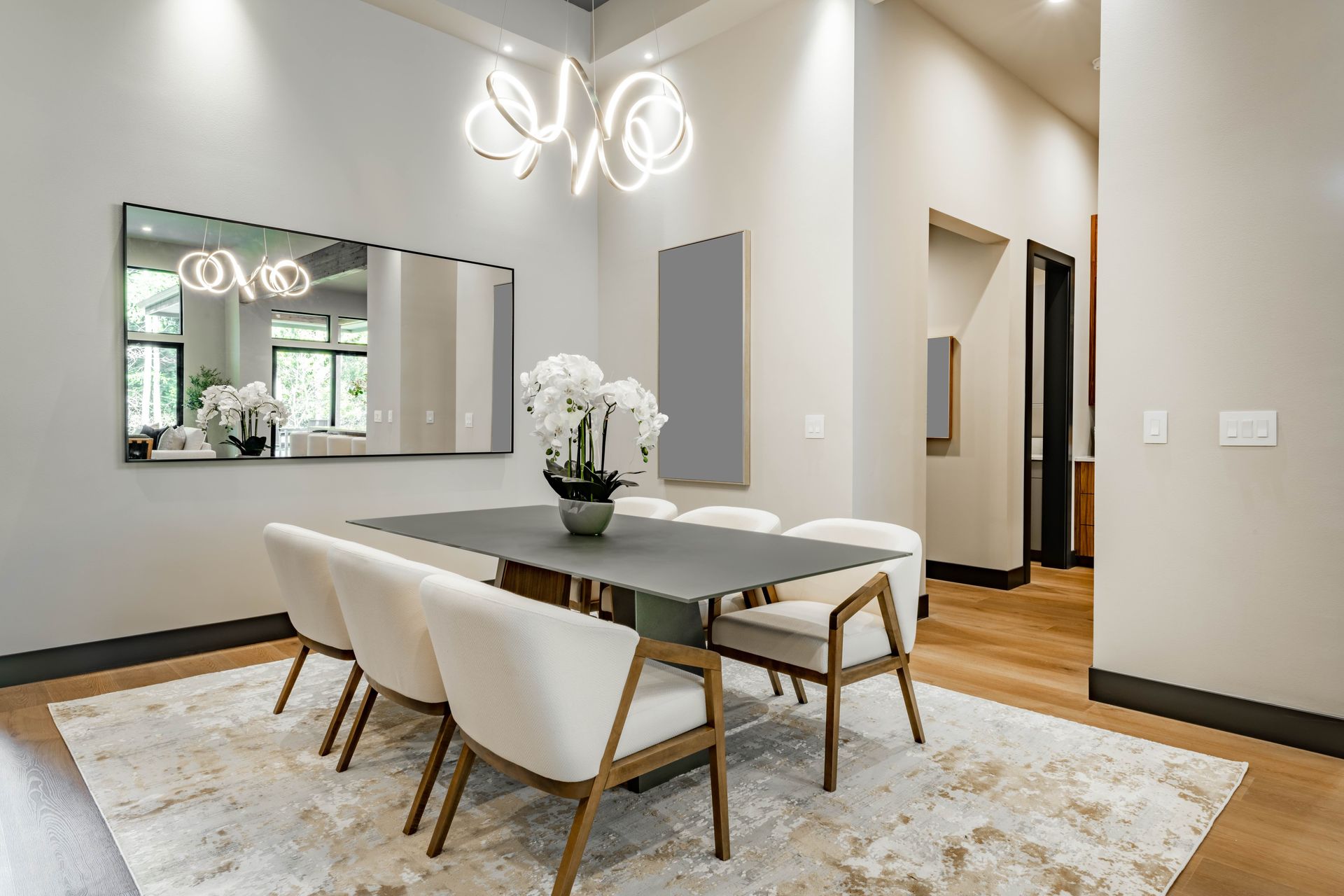 A dining room with a table and chairs and a large mirror.