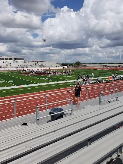 A person is running on a track in a stadium.
