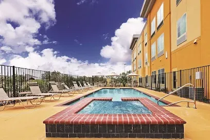 A large swimming pool with a hot tub in front of a hotel.