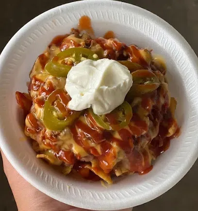 A person is holding a paper plate of food with sour cream on top