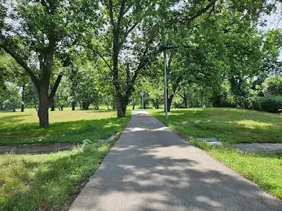 A path in a park surrounded by trees on a sunny day.
