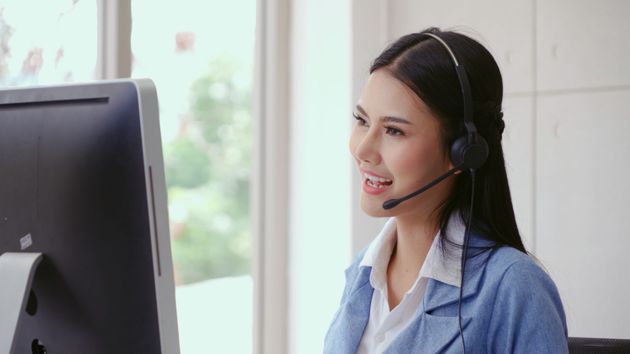 Modern apartment buildings with balconies and green roofs, surrounded by trees and grass under a blue sky.