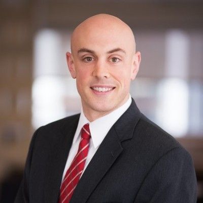 Mario T. Milano in a suit and tie is smiling for the camera.