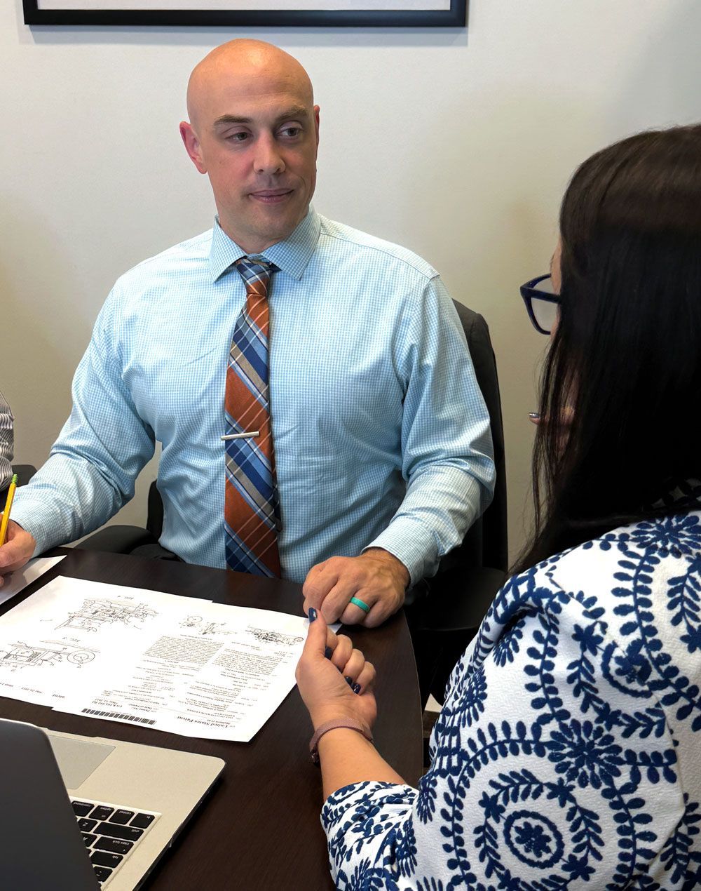 Two people in an office meeting, seated across a desk and reviewing documents together.